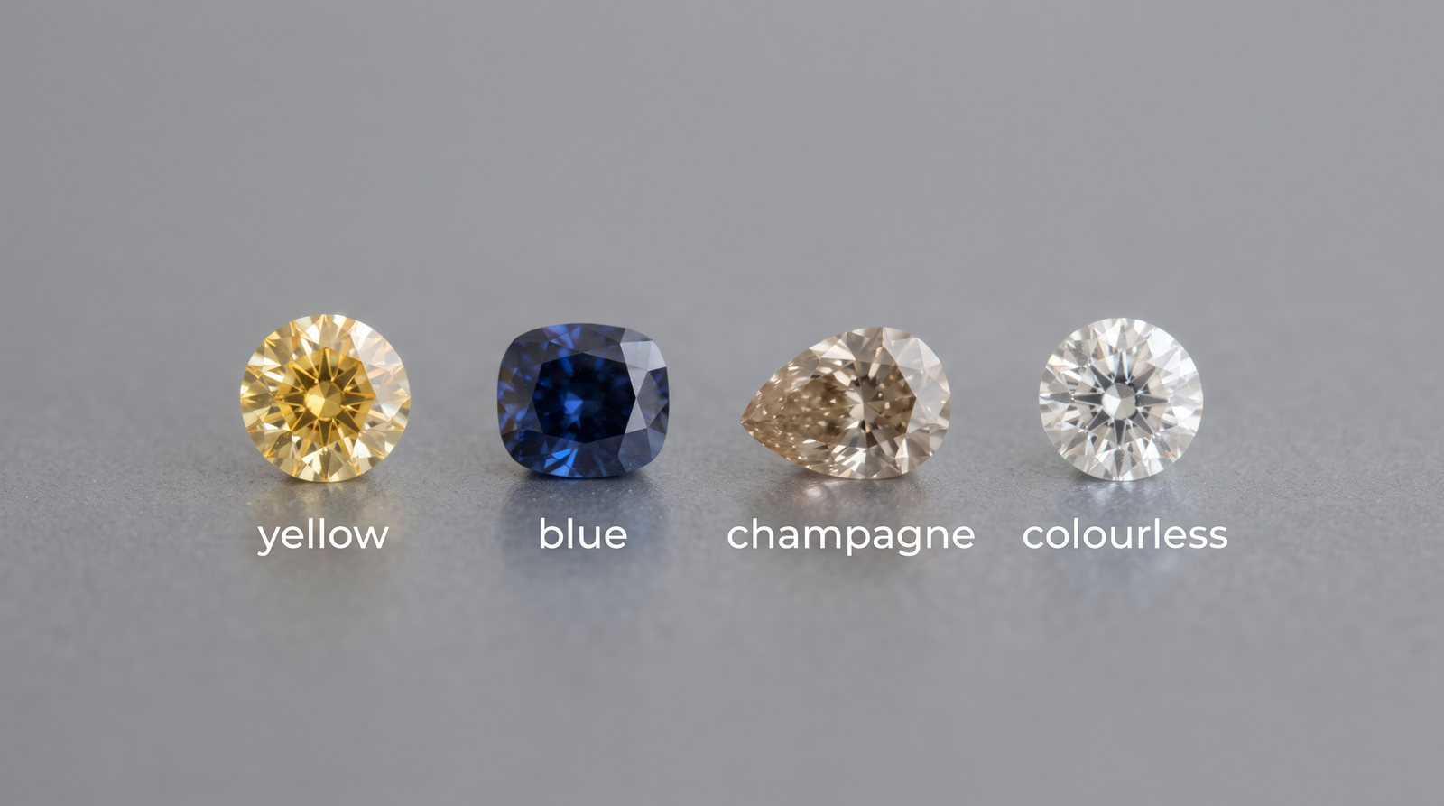 Four loose memorial diamonds in yellow, blue, champagne and colourless tones arranged in a row on a neutral grey surface