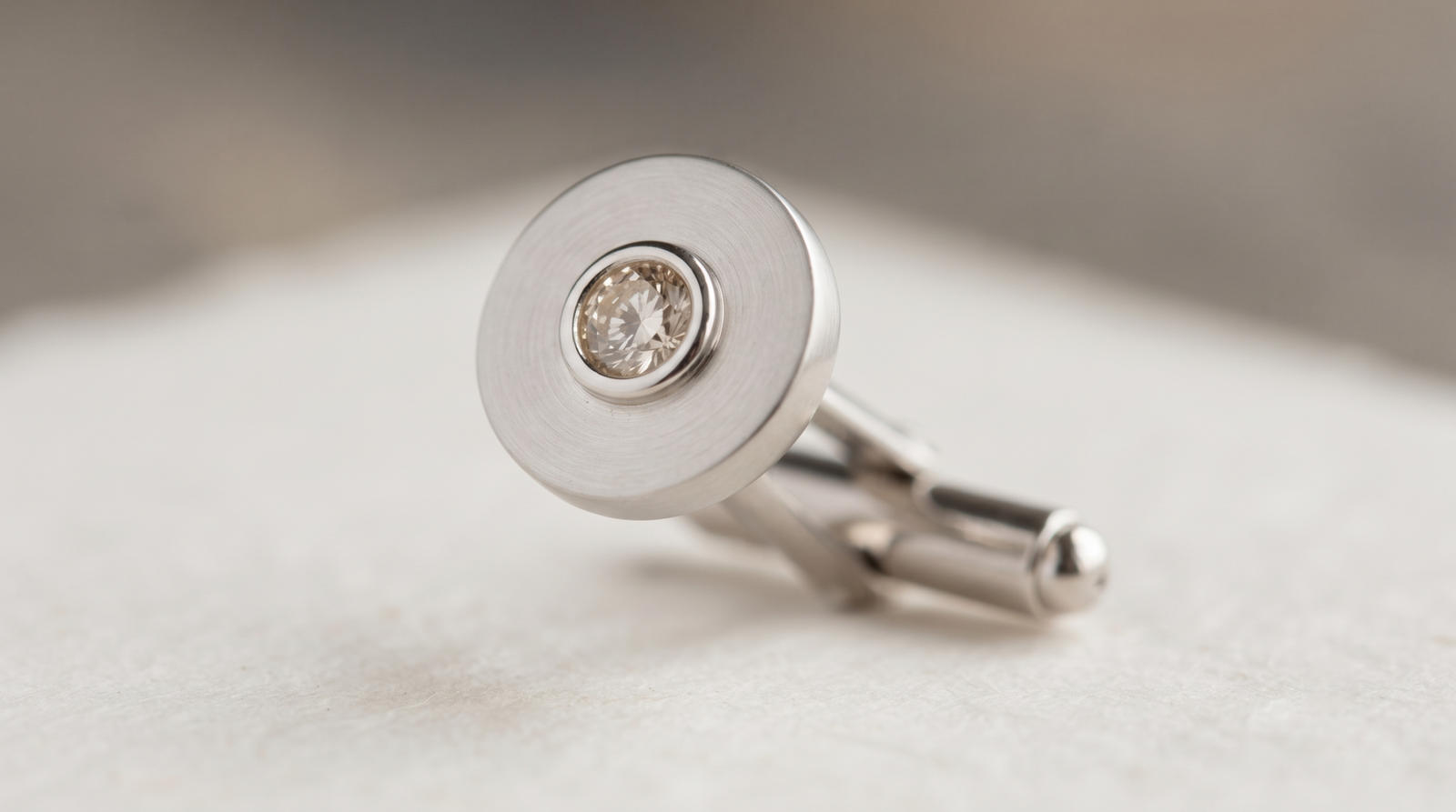 Close-up of a small diamond held in a collet on a cufflink face, back swivel visible