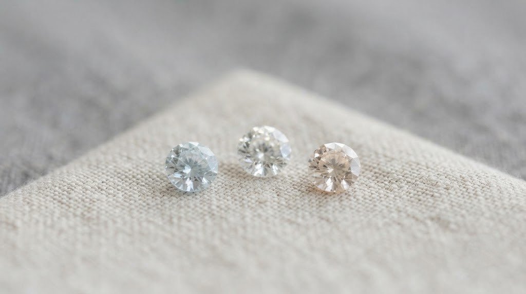 Three small loose memorial diamonds of different tones resting on a plain linen cloth