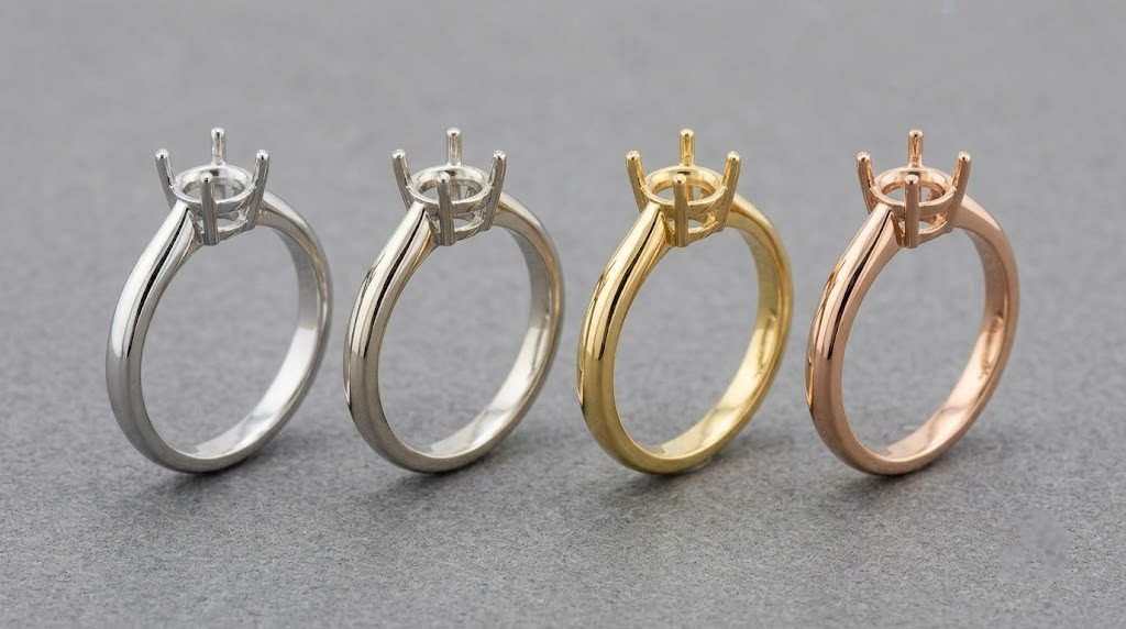 Four plain ring mounts in platinum, white gold, yellow gold and rose gold lined up side by side | Stock acceptabl